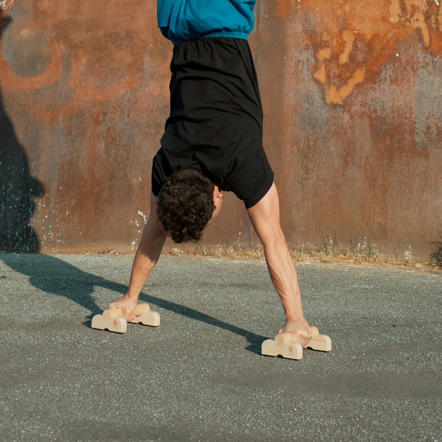 mann-macht-handstand-mit-pocketbars-vor-einer-rostigen-wand